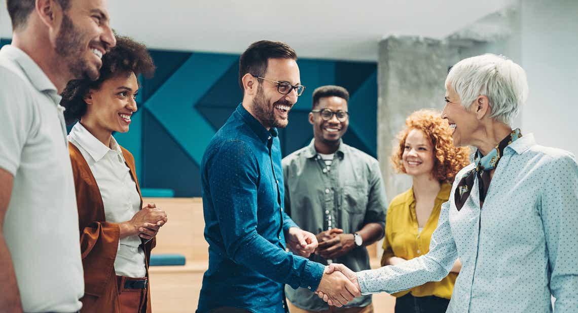 diverse group of smiling business persons shaking hands in modern office lobby