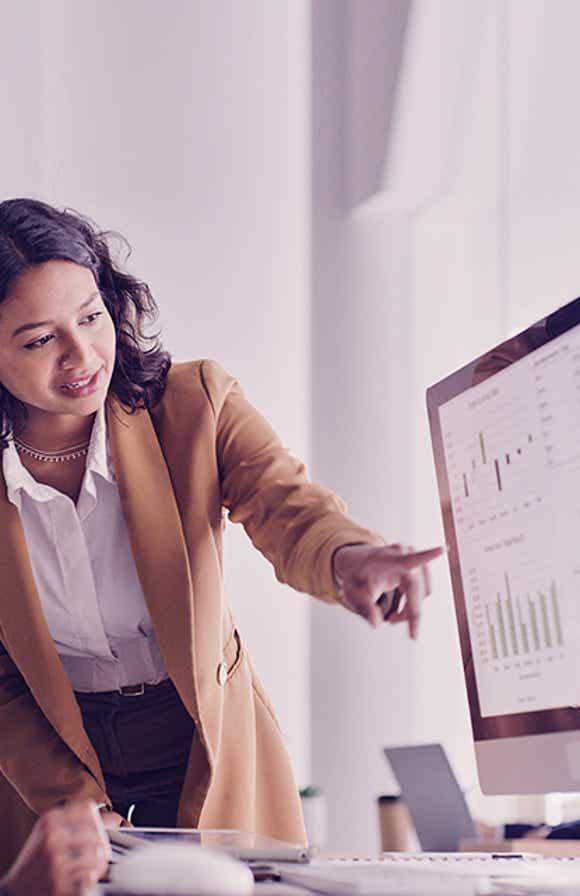 two sales managers looking at a desktop reviewing metrics that show the impact of sales training on their team's performance.